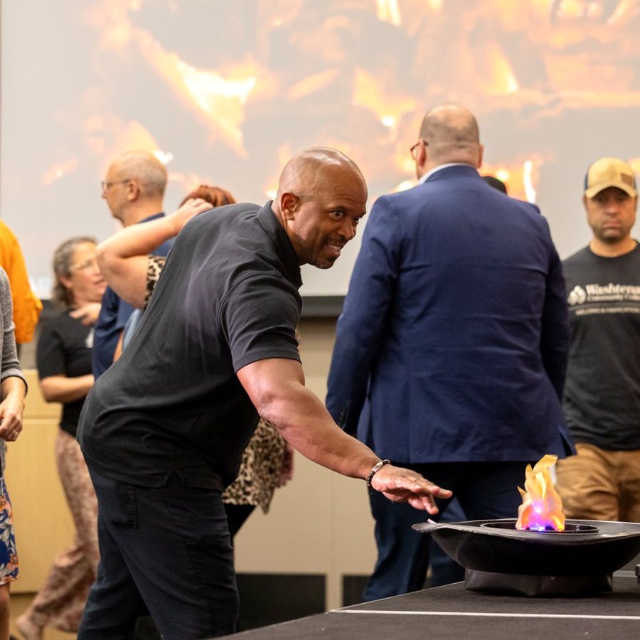 A college staff member smiles as he drops his fear card into the fire pit