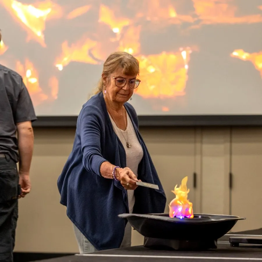 A staff member drops her fear card into the fire pit