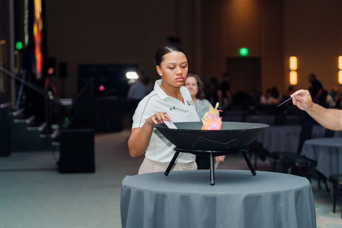 A conference attendee drops her fear card into the fire pit.