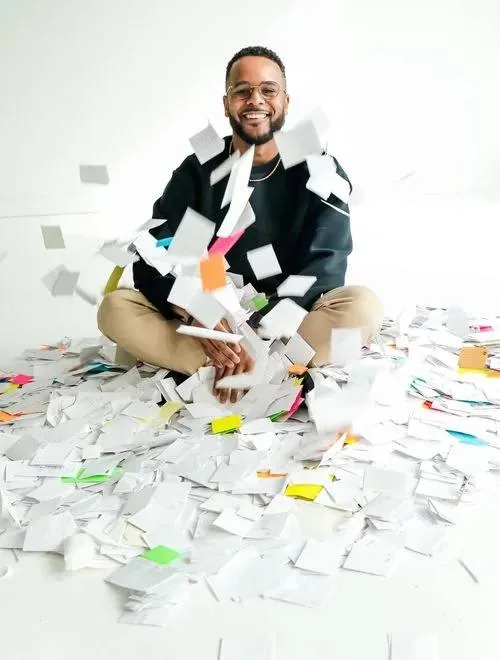 Darryl Bellamy Jr. sitting in a pile of handwritten fear cards