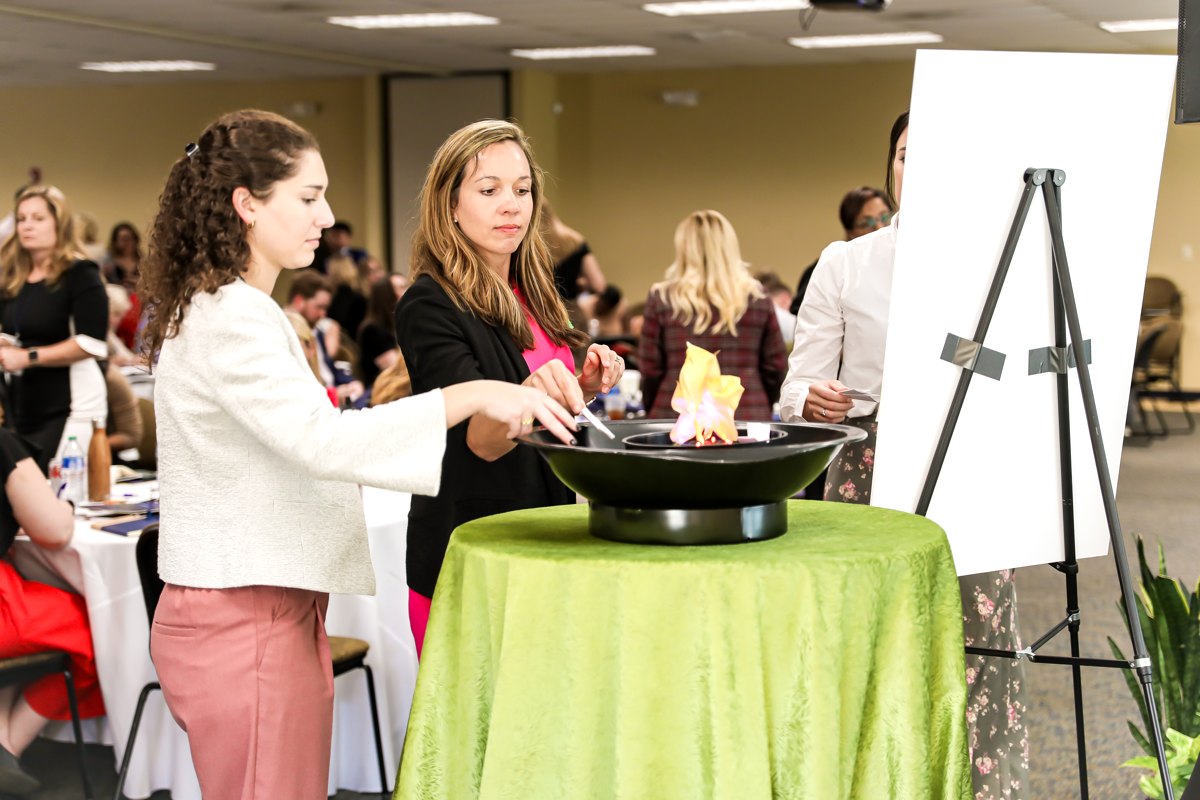 K-12 educators dropping their written fears into the fire pit during the keynote