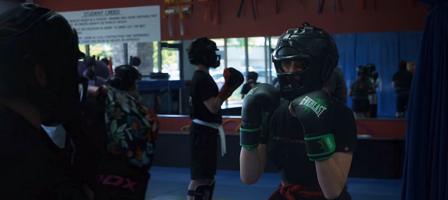 Group of martial arts students wearing protective gear and boxing gloves practicing in a training room.