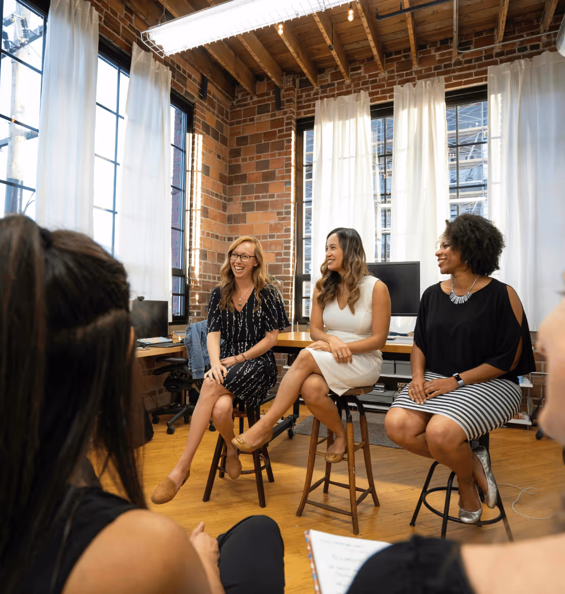 Women seated on a panel, addressing a group of attentive peers during a discussion or presentation