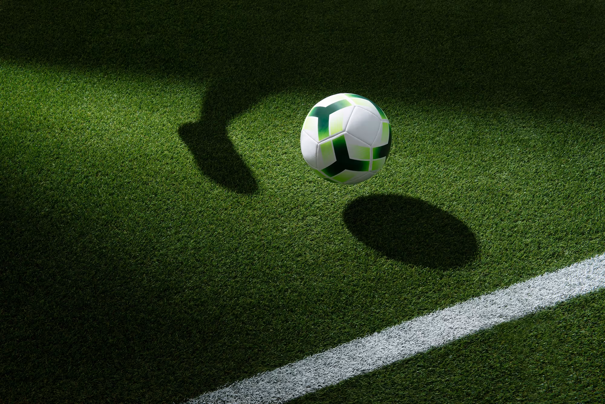 Fußball auf grünem Rasen unter LED-Flutlicht.