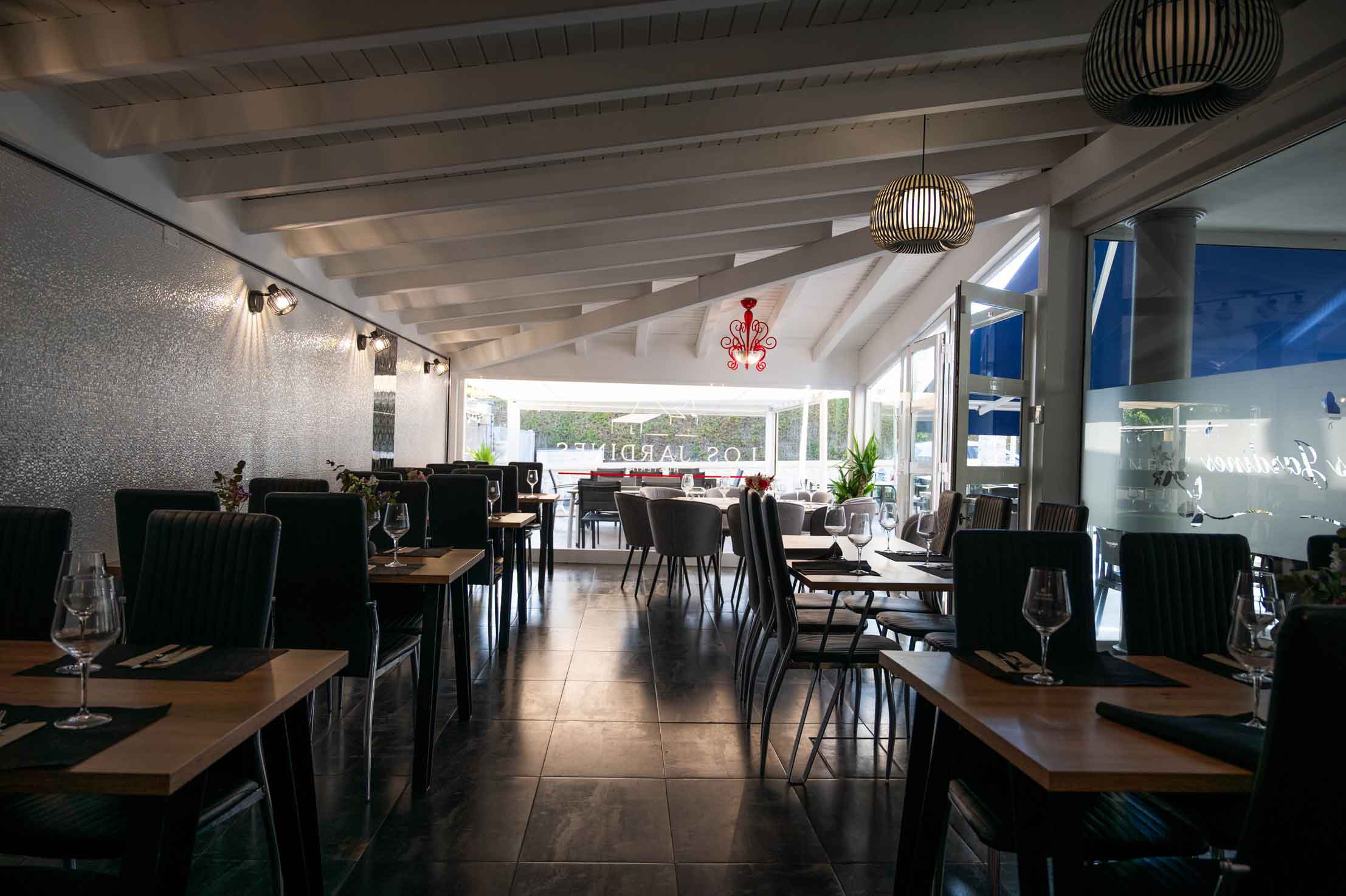 Comedor con mesas sillas preparado para las comidas en Hostería Los Jardines en Mortera