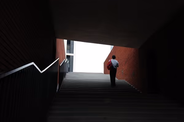 A person walks up the stairs toward the light.