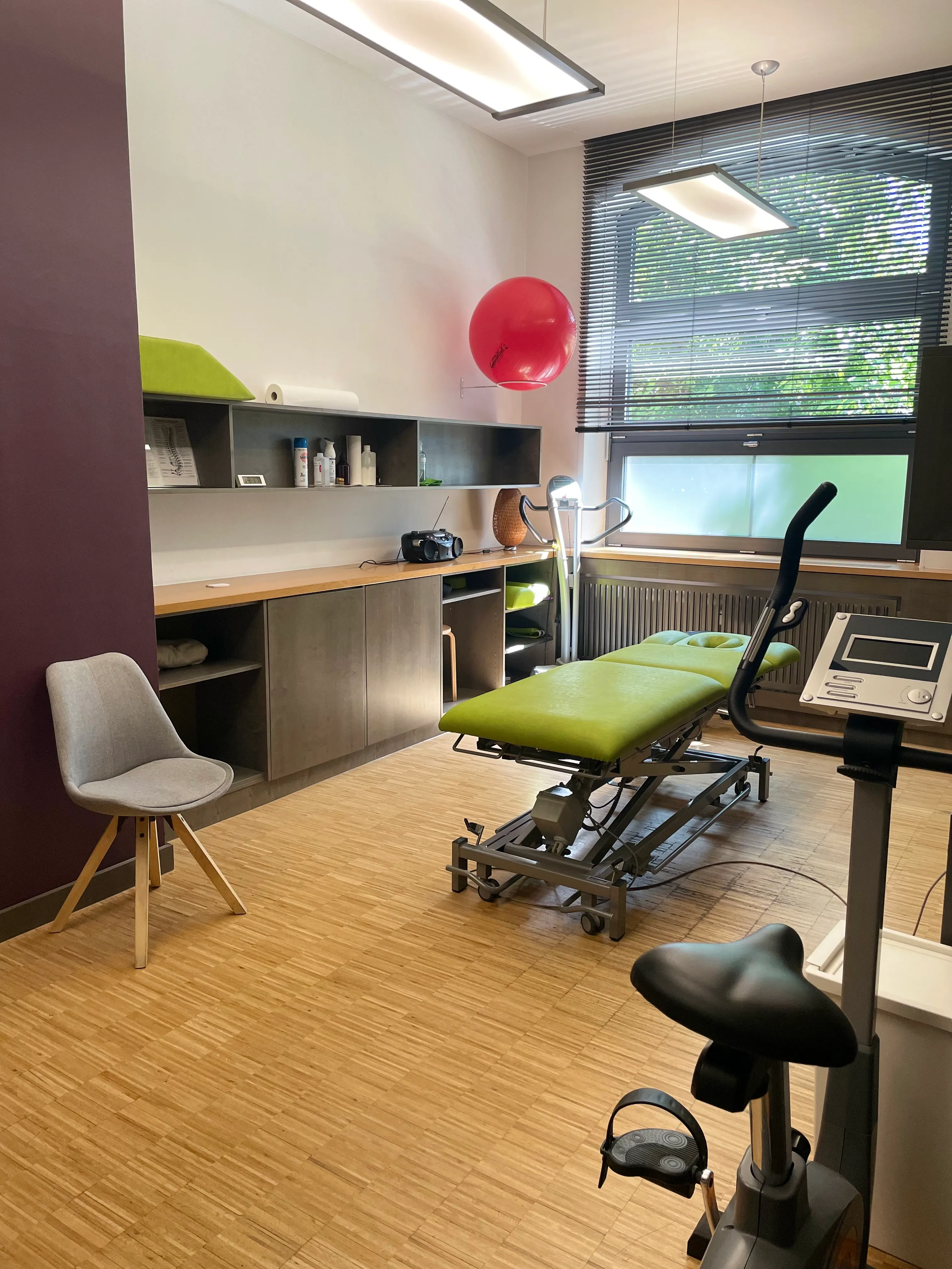 Therapieraum mit einer grünen Liege und einem Tisch.