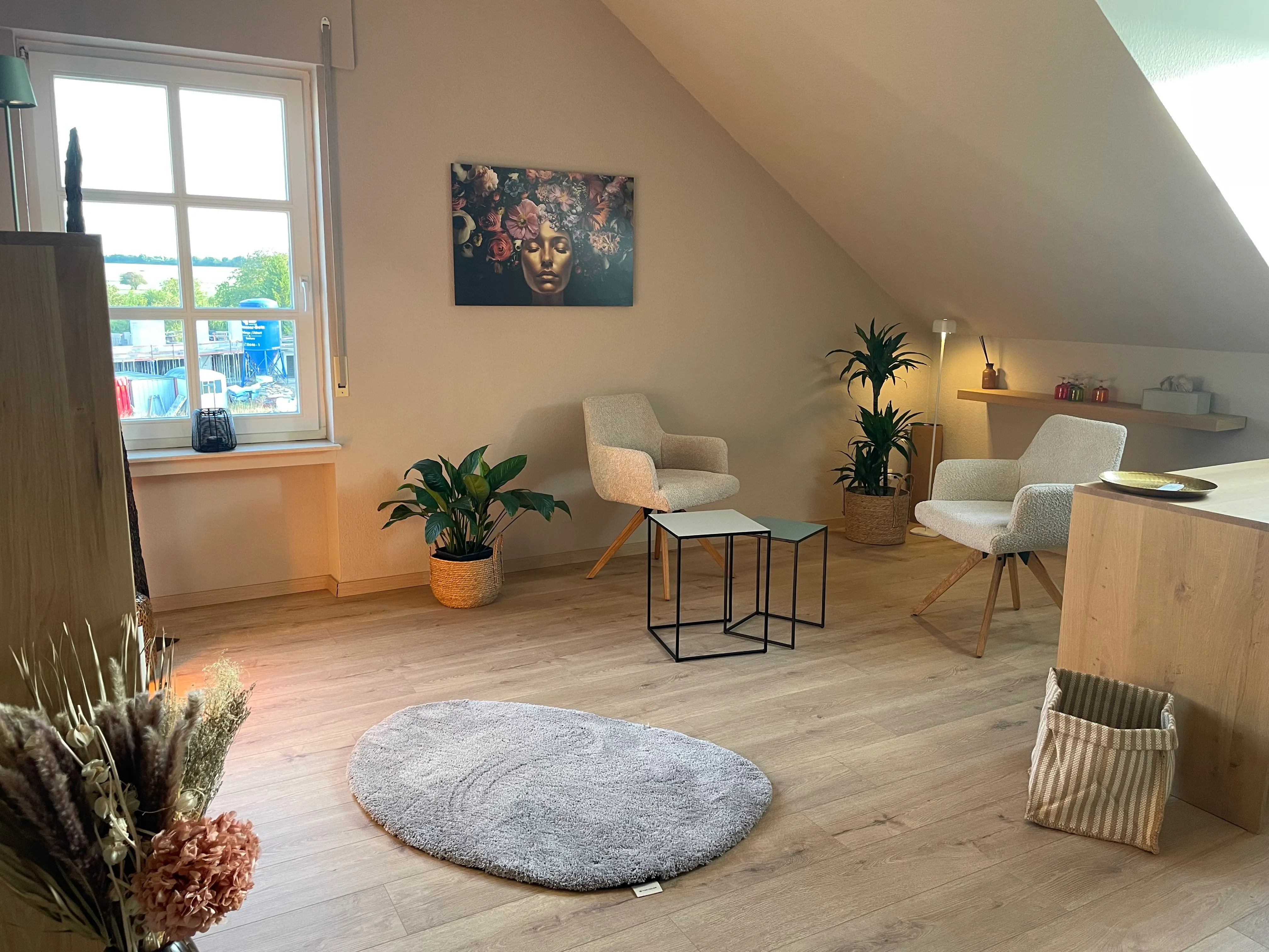 Therapieraum mit zwei Stühlen, einem kleinen Tisch und einer Pflanze.