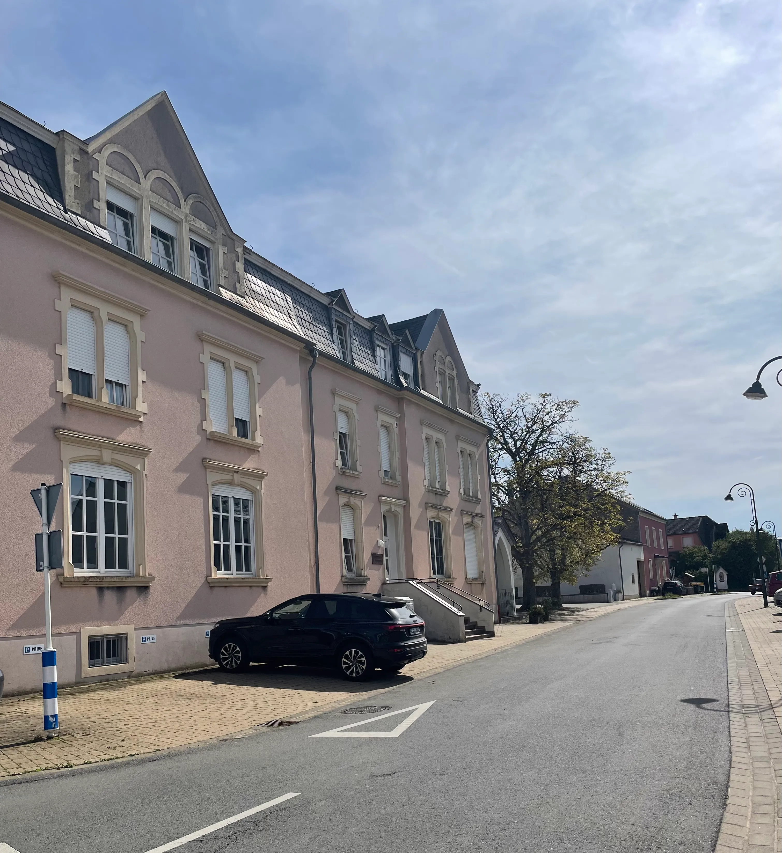 Straße mit einem geparkten schwarzen Auto auf dem Parkplatz.