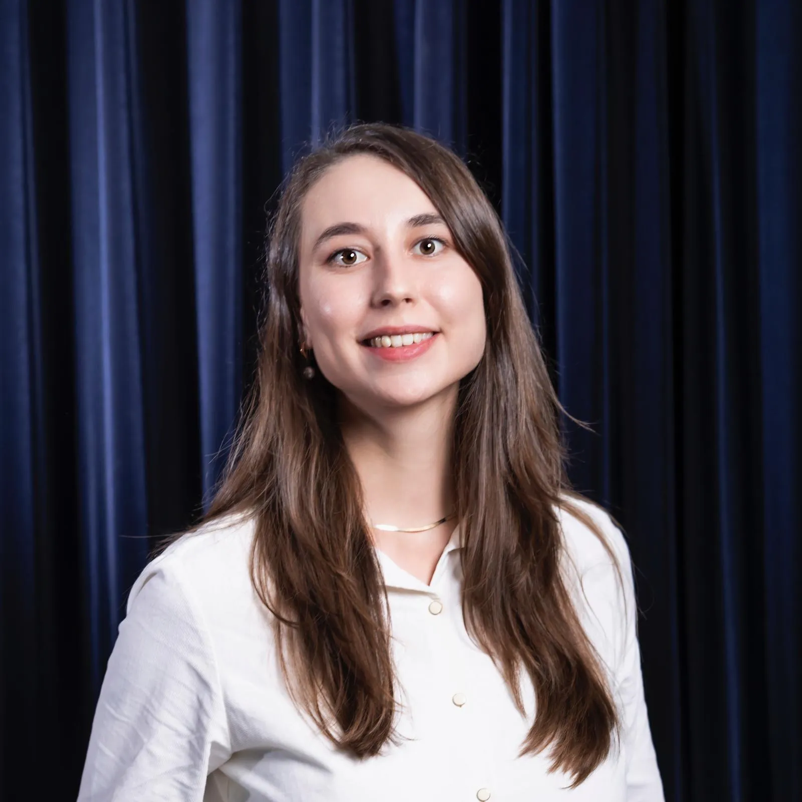 Frau mit langen Haaren vor dunkelblauem Hintergrund – professionelles Porträtfoto.