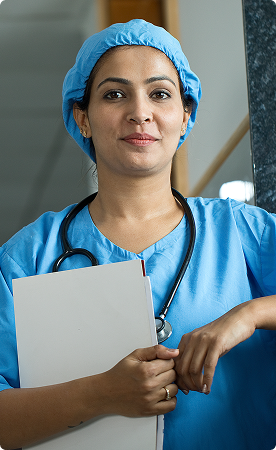 Smiling nurse wearing blue scrubs and a surgical cap, holding a clipboard with a stethoscope around her neck.