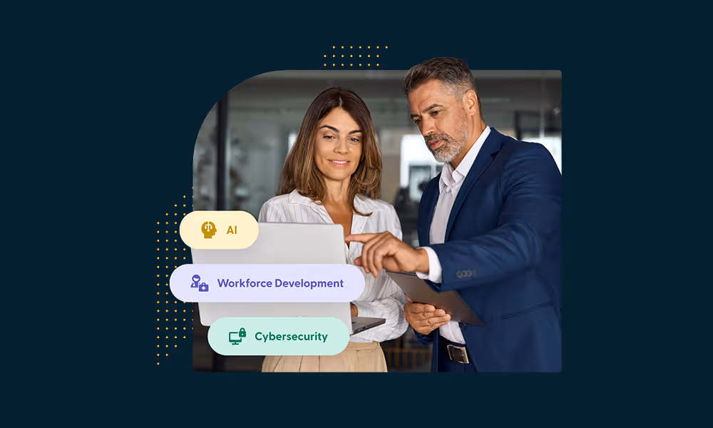 Man in a blue suit pointing at a laptop held by a woman in a white blouse, with tags reading AI, Workforce Development, and Cybersecurity.