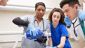 Medical team with blue gloves performing resuscitation using a bag valve mask on a patient.