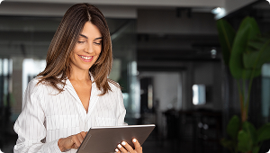 Smiling woman using a tablet in a modern office environment.