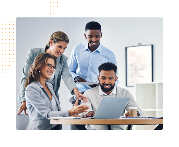 Four diverse professionals collaborating and smiling while looking at a laptop in an office.