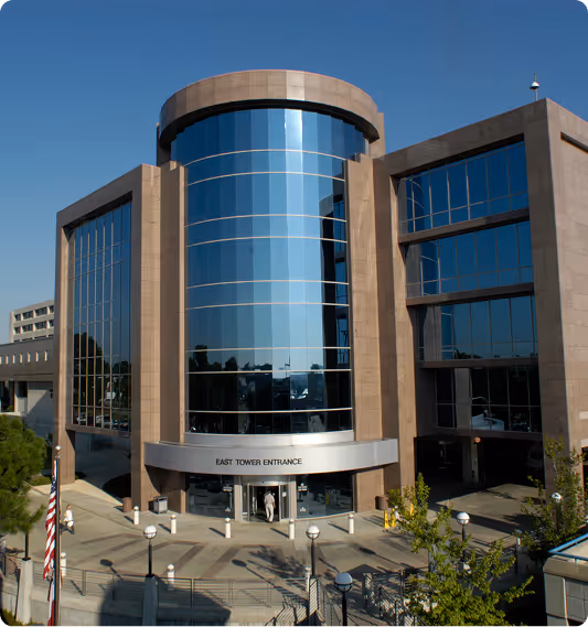 Modern office building with reflective glass facade and a sign reading East Tower Entrance.