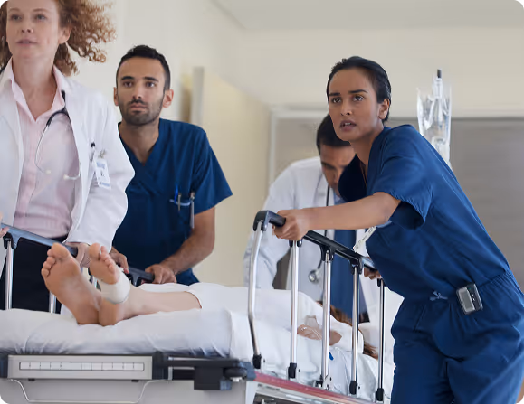 Medical team urgently pushing patient on stretcher through hospital corridor.