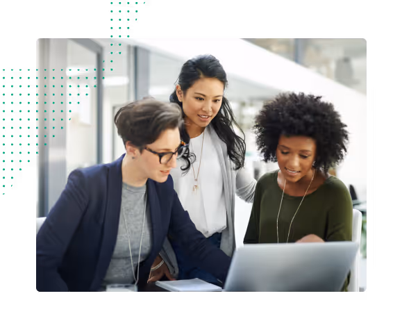 Three diverse women collaborating and looking at a laptop screen in a bright office setting.