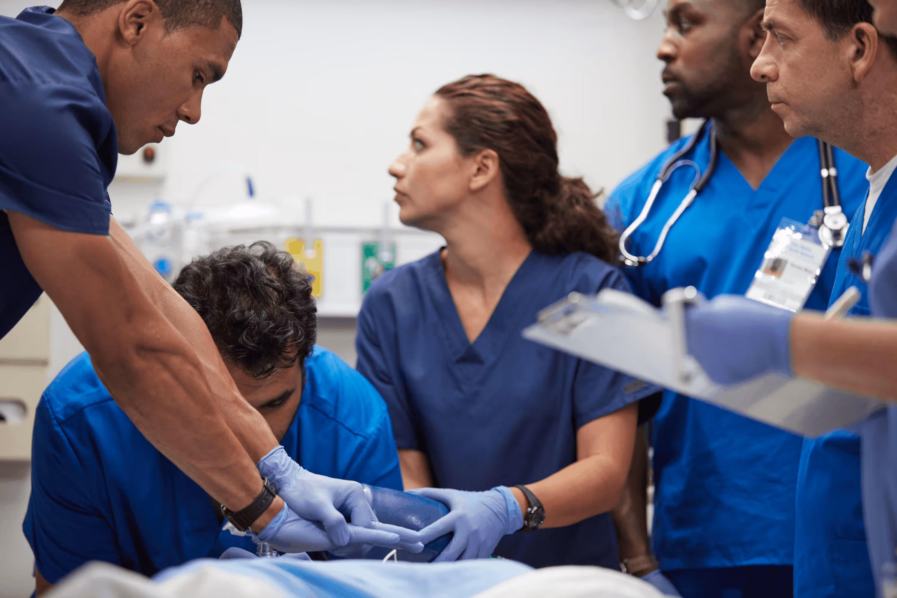 Medical team in blue scrubs working together in a hospital emergency room setting.