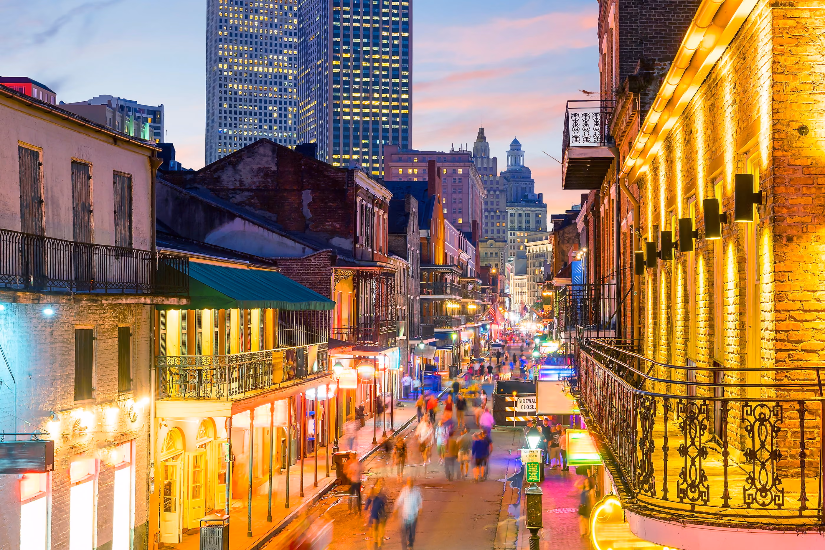 Vibrant evening street scene with historic buildings, balconies, and blurred people in a lively city.