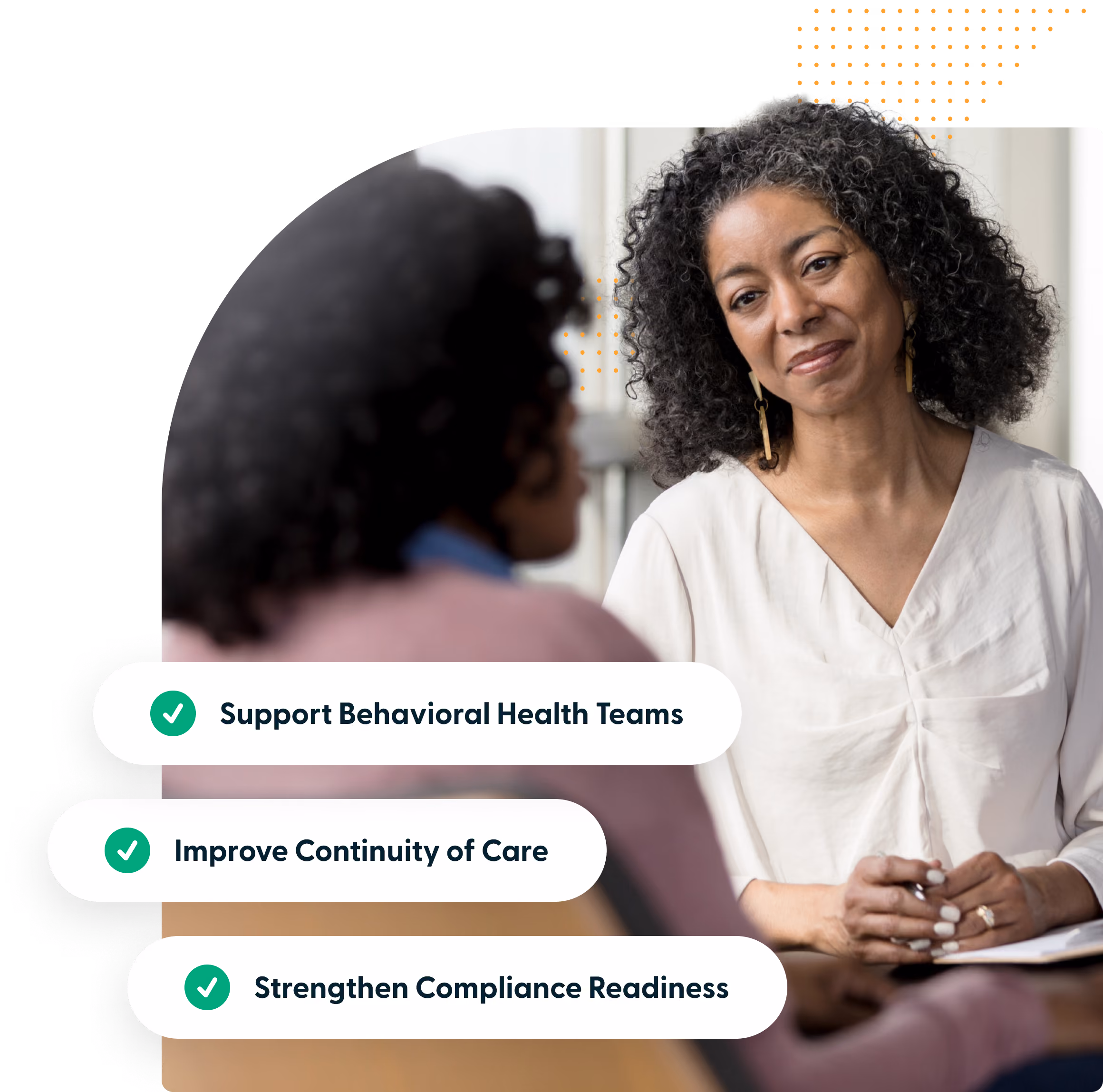 An older woman with curly gray hair listens attentively while holding a pen and paper, engaged in conversation with another person whose back is to the camera; graphic text overlays list three goals: Support Behavioral Health Teams, Improve Continuity of Care, and Strengthen Compliance Readiness, each accompanied by a green checkmark.