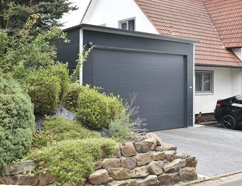 Großzügige Einzelgarage aus wärmegedämmten Sandwichpaneelen mit anthrazitfarbenem Sektionaltor in Überhöhe – ideal für PKW, Transporter oder Werkstattnutzung