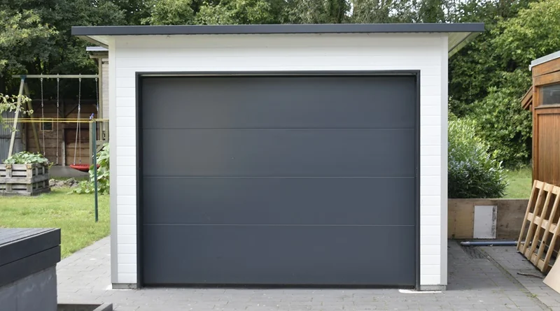 Moderne Einzelgarage aus hochwertigen Sandwichpaneelen mit Design-Sektionaltor in Anthrazit, freistehend im Garten