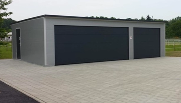Großraum-Doppelgarage aus wärmedämmenden Sandwichpaneelen in Sondermaßen, mit zwei anthrazitfarbenen Sektionaltoren – geeignet auch für Feuerwehrfahrzeuge