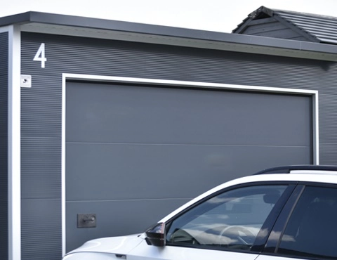 Designorientierte Anbaugarage aus wärmegedämmten Sandwichpaneelen mit anthrazitfarbenem Sektionaltor – platzsparende und moderne Lösung für PKW