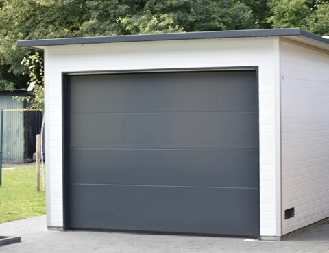Freistehende Einzelgarage aus wärmedämmenden Sandwichpaneelen mit weißer Fassade und anthrazitfarbenem Sektionaltor – moderne Lösung für Pkw