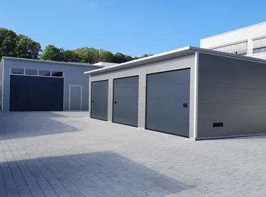 Moderne Garagenanlage mit drei Sektionaltoren und angrenzender Großraumhalle aus wärmedämmenden Sandwichpaneelen, vielseitig nutzbar für Pkw und gewerbliche Fahrzeuge