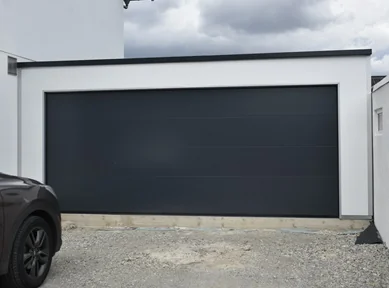 Doppelgarage aus Sandwichpaneelen mit weißer Fassade und anthrazitfarbenem Sektionaltor, wärmegedämmt und modern gestaltet. Ideal für Pkw