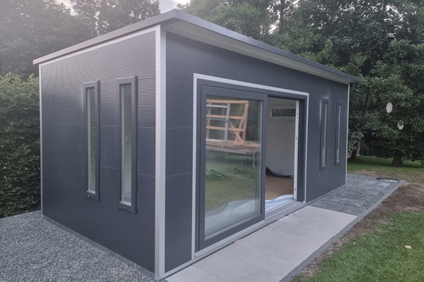 Modernes Gartenhaus aus Sandwichpaneelen in Anthrazit mit Flachdach, großen Schiebetüren aus Glas und schmalen Hochfenstern