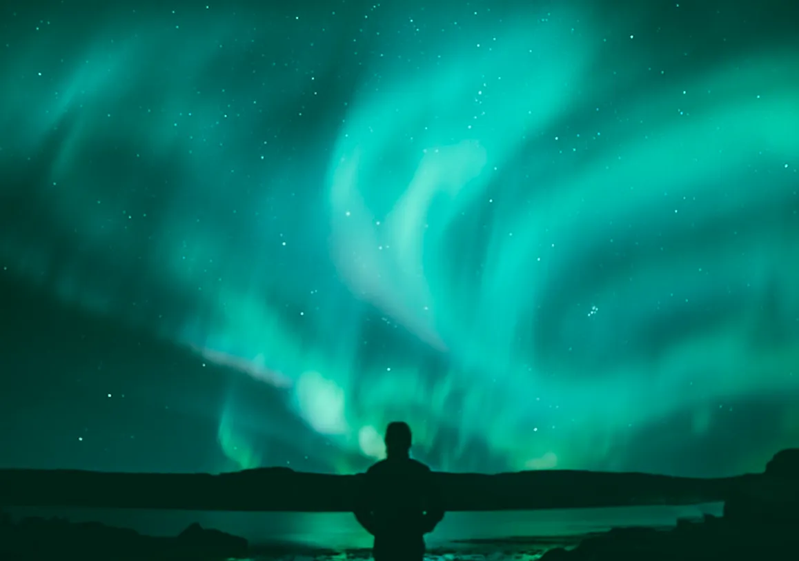 Silhouette watching vivid aurora sky.