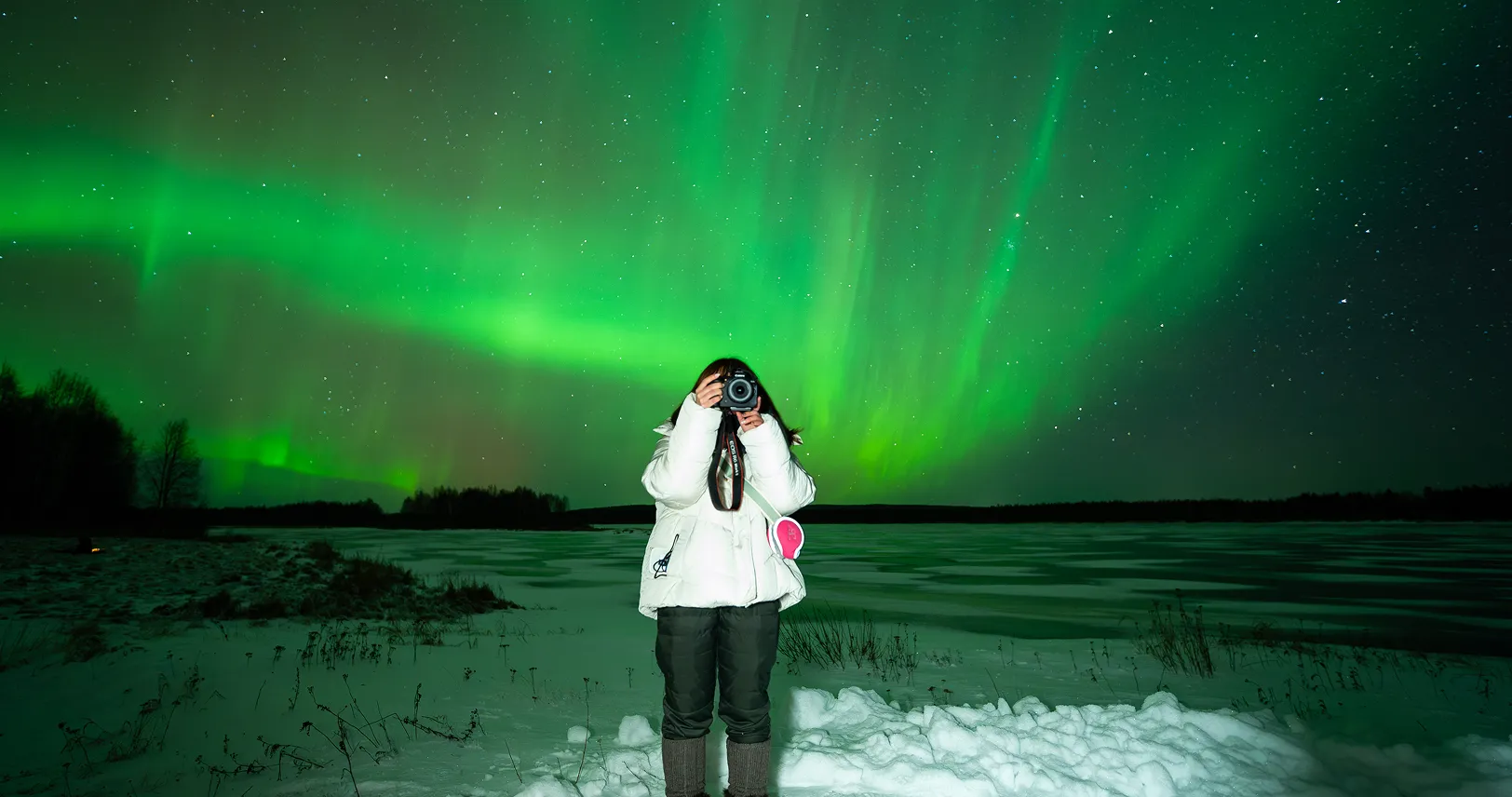 Woman taking photo of northern lights.