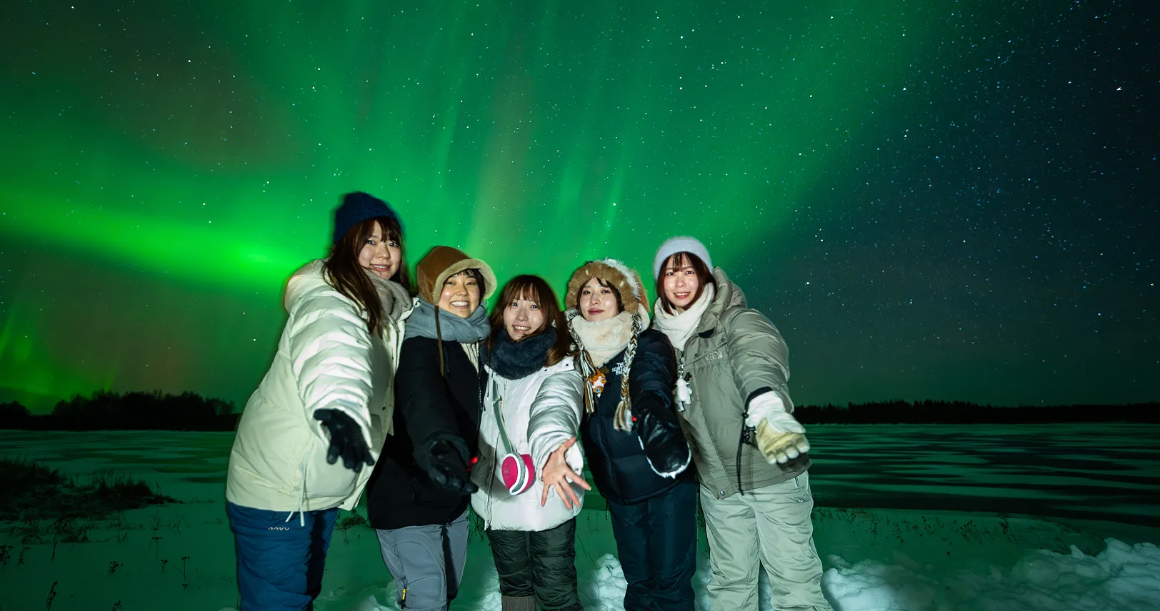Five women smiling under glowing sky.