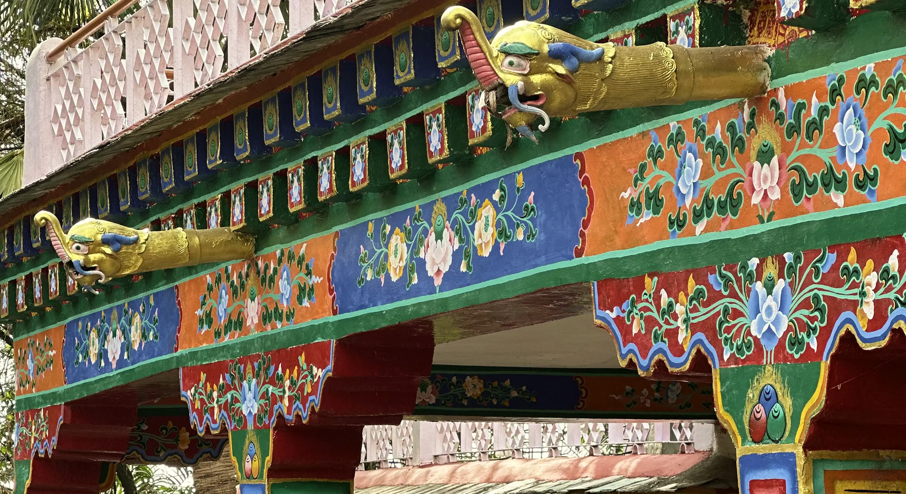 Colorful, intricate Tibetan temple eaves with golden dragon heads and vibrant floral patterns.