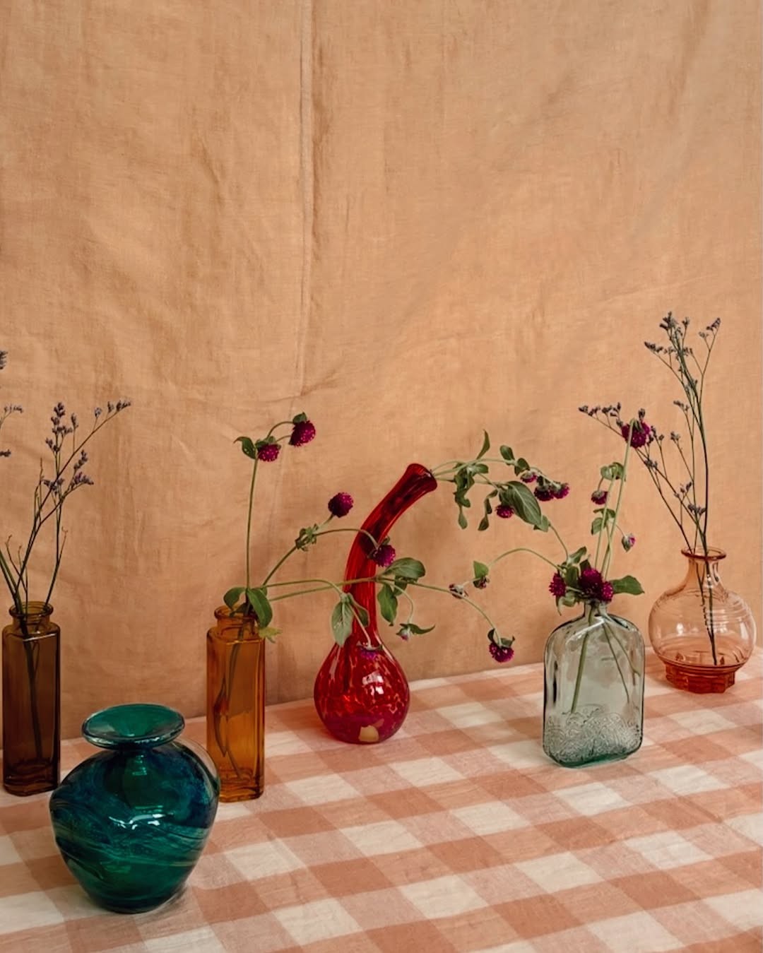 Coloured glass vases with single stem flowers 