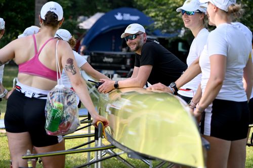 Rudertrainer mit Ruderinnen im Trainingsoutfit des deutschen Teams mit dem gelben Achter stehen auf dem Bootsplatz
