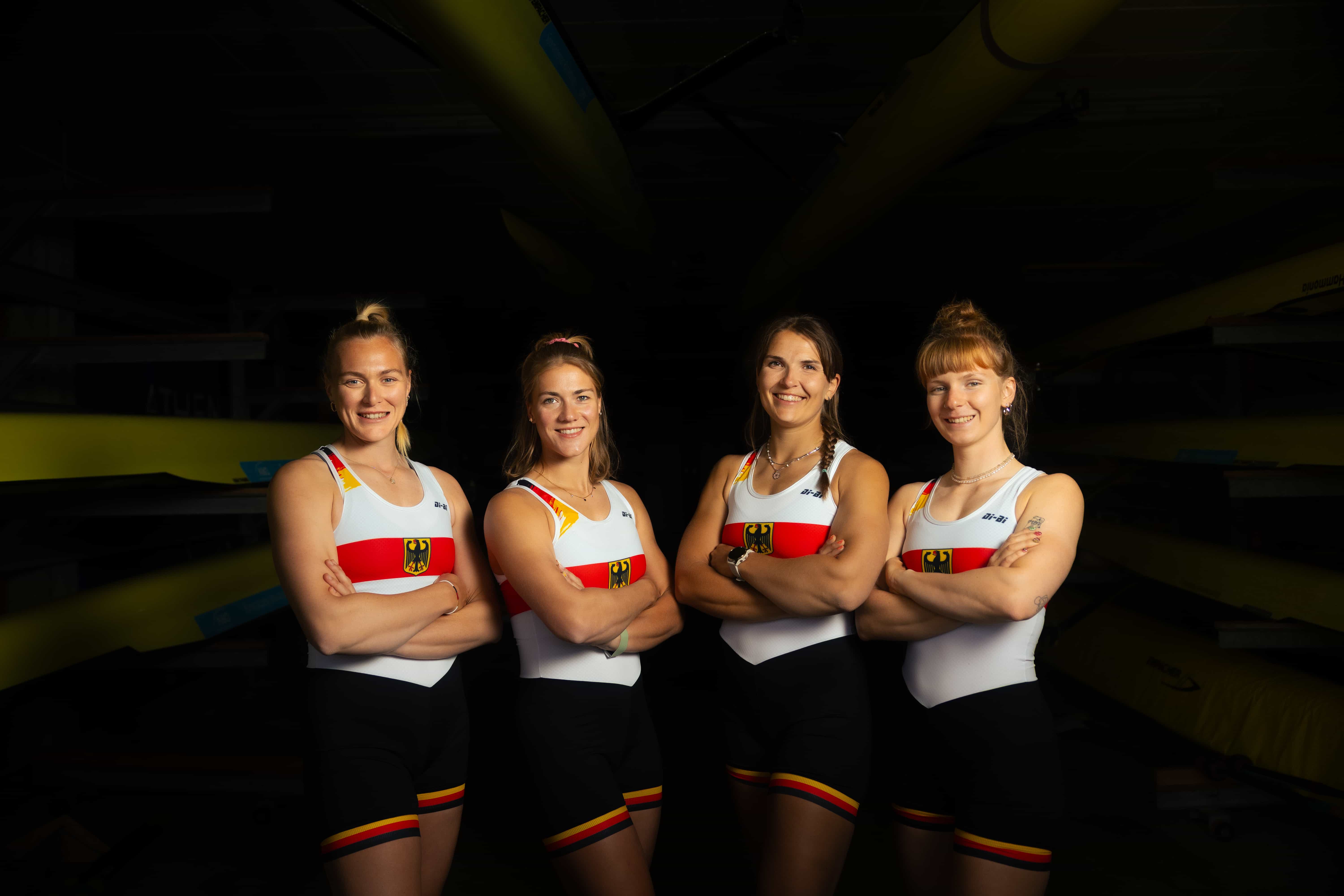 Vier Ruderinnen im Trainingsoutfit des deutschen Teams posieren für den Fotografen vor schwarzem Hintergrund