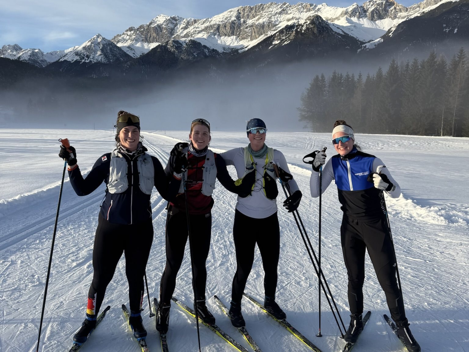 Tabea Kuhnert, Annabelle Bachmann, Olivia Clotten und Michelle Lebahn auf Langlauf-Skiern in der Schneelandschaft mit verschneiten Bergen im Hintergrund