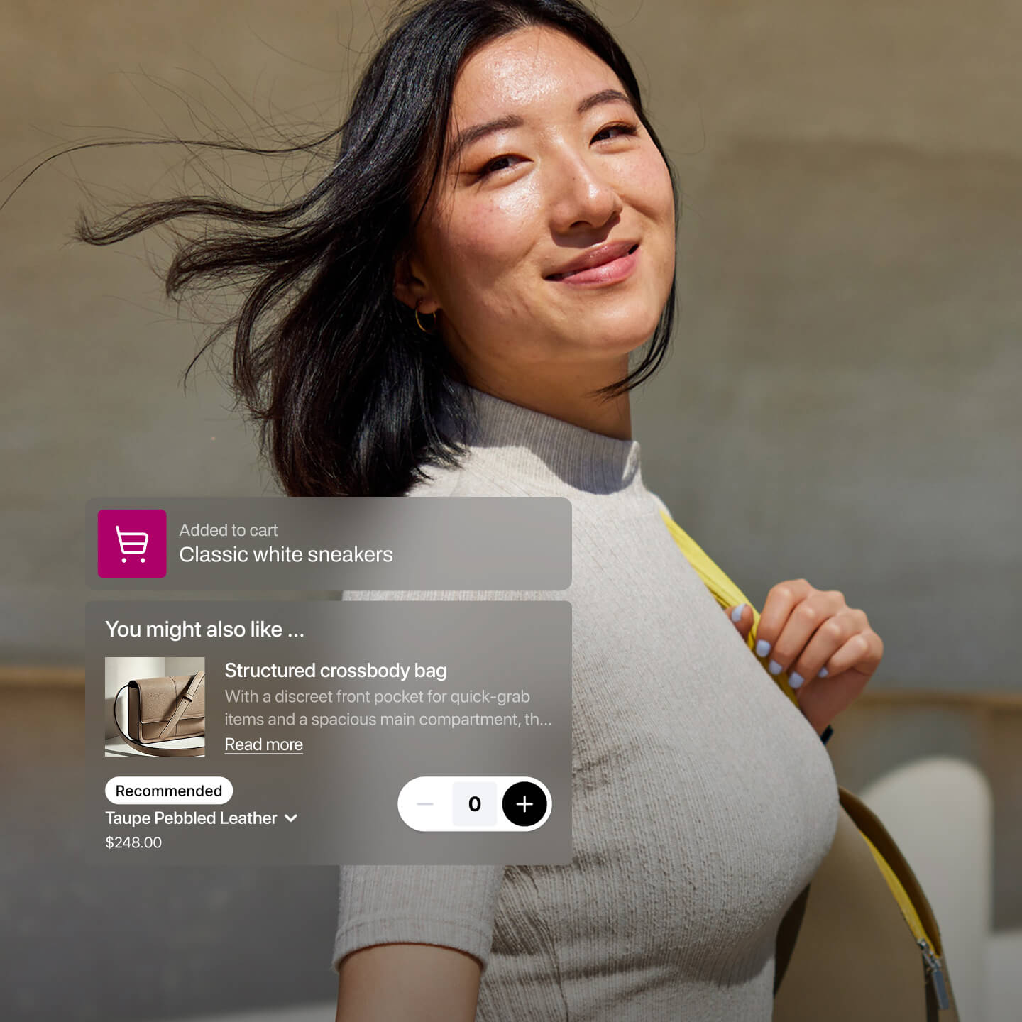 A woman with shoulder-length dark hair smiles gently while walking outside in sunlight, holding the strap of a yellow handbag. An overlay shows that “Classic white sneakers” were added to her cart, along with a product recommendation for a “Structured crossbody bag” in taupe pebbled leather, priced at $248. The clean, minimalist background keeps the focus on the user experience and product suggestion.