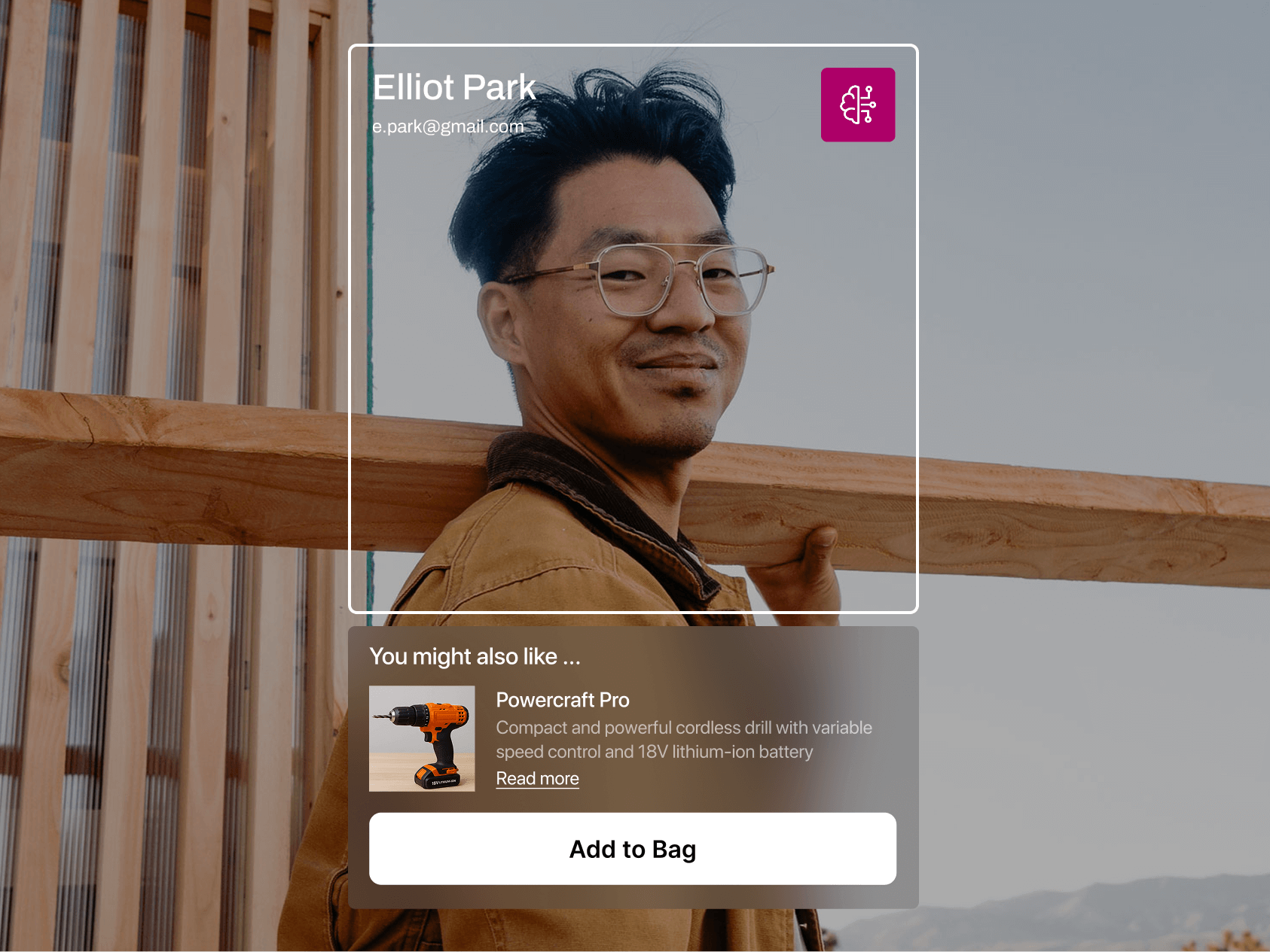 A man wearing glasses and a tan work jacket carries a long wooden beam on his shoulder while smiling slightly at the camera. An on-screen overlay identifies him as "Elliot Park" with his email address, alongside an AI icon—suggesting a smart tool or profile recognition feature. Below, a product suggestion window recommends a cordless drill called “Powercraft Pro” with an “Add to Bag” button, blending personalized e-commerce with a hands-on construction setting.