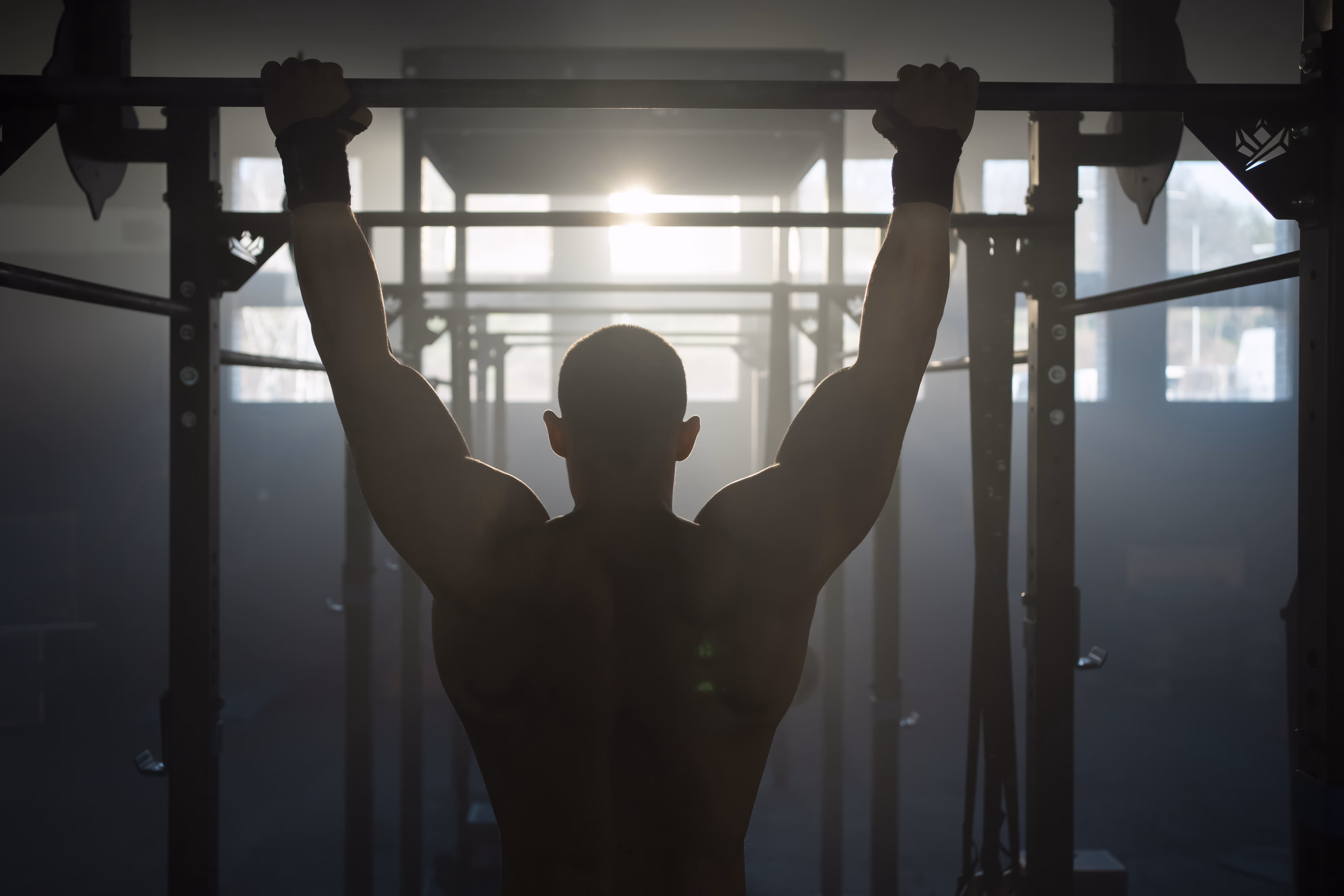 A man is doing a pull up in the gym.