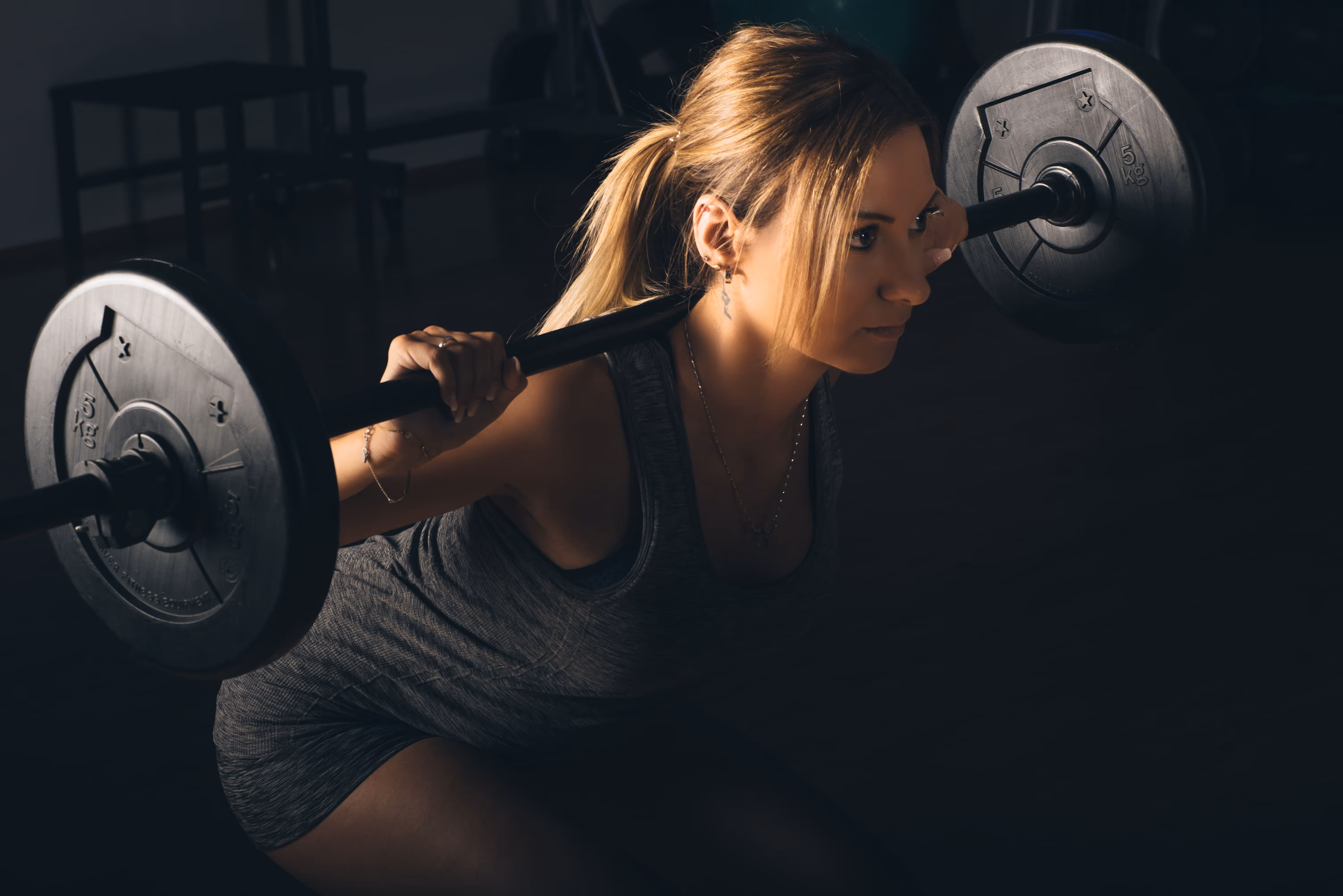 A woman lifting a barbell in a gym.