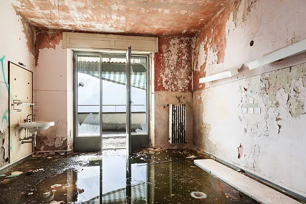 Abandoned, water-damaged room with peeling walls and flooded floor