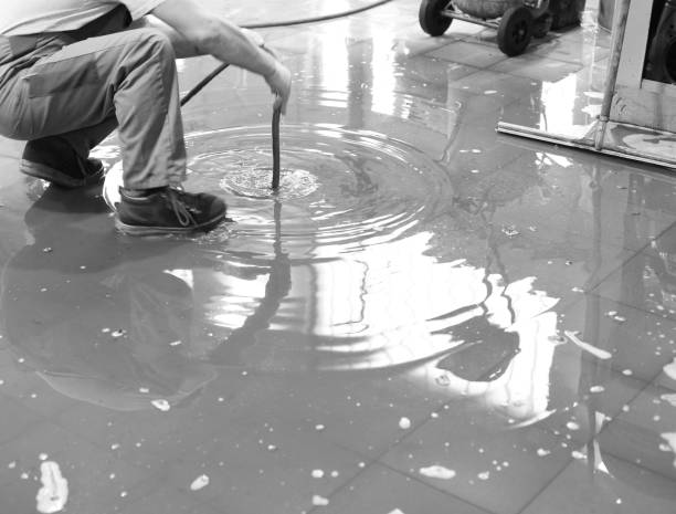Person stirring puddle of water on reflective floor with mop