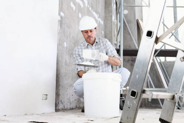 Construction worker in white hard hat mixing materials at building site