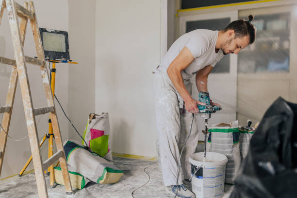 Worker mixing paint with power drill in home renovation project