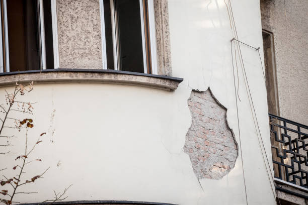 Damaged white building wall with exposed bricks and curved window